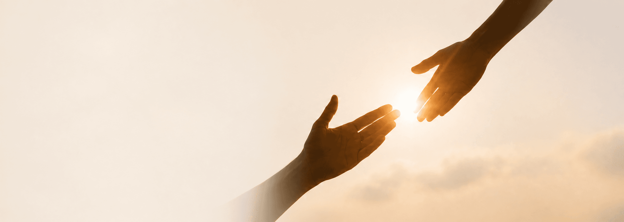 Dos manos acercándose bajo una luz cálida